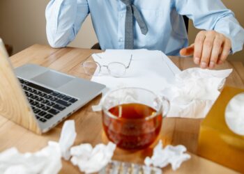 Sick man while working in office, businessman caught cold, seasonal flu.