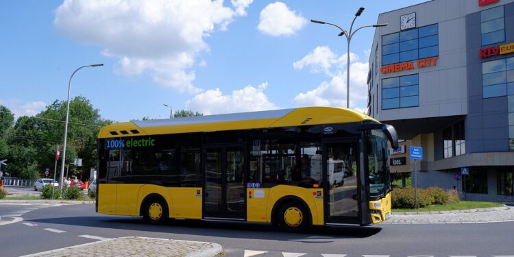 Żółty autobus elektryczny Solaris Urbino z oznaczeniem 100% electric na trasie miejskiej