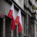 Flagi Polski wywieszone na elewacji kamienicy przy miejskiej ulicy