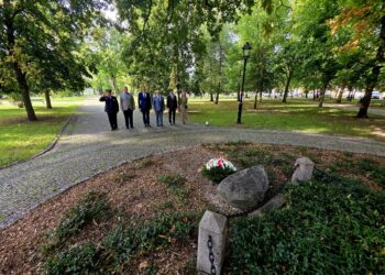 Delegacja władz Suwałk przed kamieniem pamiątkowym z biało-czerwonym wieńcem w parku
