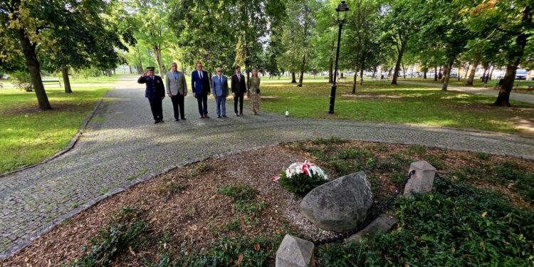 Delegacja władz Suwałk przed kamieniem pamiątkowym z biało-czerwonym wieńcem w parku