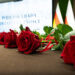 Czerwone róże na stole, w tle ekran z napisem Podlaska Rada Długowieczności oraz flagi Polski i Unii Europejskiej