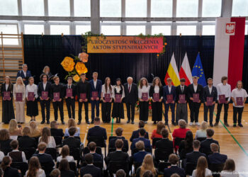 Stypendyści prezydenta Białegostoku z aktami stypendialnymi podczas uroczystości w hali sportowej