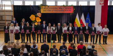 Stypendyści prezydenta Białegostoku z aktami stypendialnymi podczas uroczystości w hali sportowej