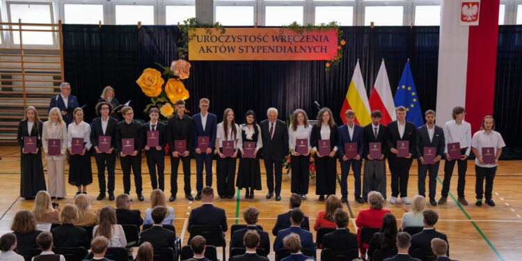 Stypendyści prezydenta Białegostoku z aktami stypendialnymi podczas uroczystości w hali sportowej
