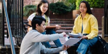 Studenci na schodach uczelni z książkami