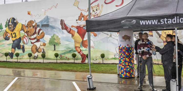 Mural przedstawiający sportowe żubry i maskotki na ścianie przy Chorten Arenie w Białymstoku