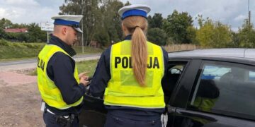 Policjanci z drogówki podczas kontroli samochodu na poboczu drogi