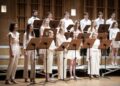 Chór Młodzieżowy Opery i Filharmonii Podlaskiej podczas koncertu, śpiewacy w jasnych strojach przy pulpitach z nutami