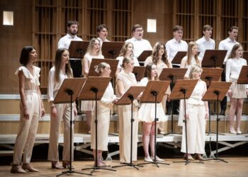 Chór Młodzieżowy Opery i Filharmonii Podlaskiej podczas koncertu, śpiewacy w jasnych strojach przy pulpitach z nutami