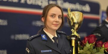 Policjantka z pucharem i kwiatami podczas finału zawodów Dzielnicowy Roku