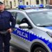 Policjant stojący przy radiowozie na ulicy w Szczuczynie