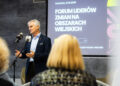 Mężczyzna przemawia przy mikrofonie, w tle baner Forum Liderów Zmian na Obszarach Wiejskich