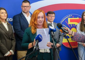 Konferencja prasowa w Szkole Podstawowej nr 5 w Białymstoku, kobieta mówi do mikrofonów, obok uczniowie i przedstawiciele miasta