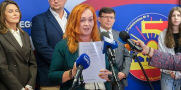 Konferencja prasowa w Szkole Podstawowej nr 5 w Białymstoku, kobieta mówi do mikrofonów, obok uczniowie i przedstawiciele miasta