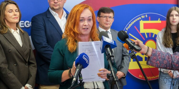 Konferencja prasowa w Szkole Podstawowej nr 5 w Białymstoku, kobieta mówi do mikrofonów, obok uczniowie i przedstawiciele miasta