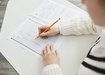 Uczeń wypełnia ołówkiem kartę odpowiedzi testu na szkolnej ławce