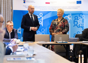 Uczestnicy posiedzenia komitetu przy stole konferencyjnym, w tle baner projektu