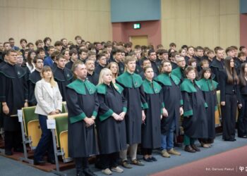 Uczniowie w czarno-zielonych togach podczas ślubowania pierwszoklasistów w auli Politechniki Białostockiej
