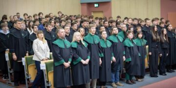 Uczniowie w czarno-zielonych togach podczas ślubowania pierwszoklasistów w auli Politechniki Białostockiej