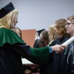 Uczniowie w czarno-zielonych togach podczas ślubowania pierwszoklasistów w auli Politechniki Białostockiej